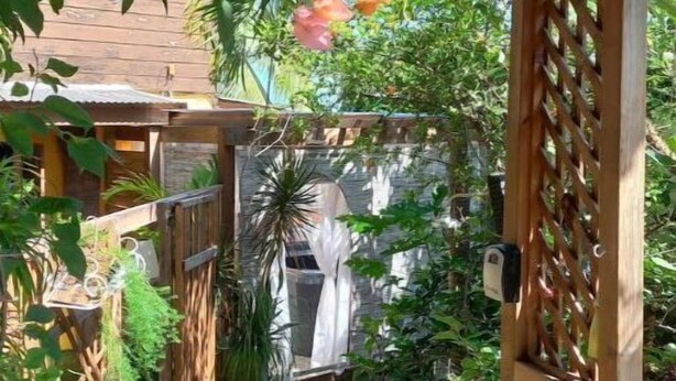 En pergola av trä med rosa blommor, ett staket av trä och en trädgårdsgång.