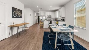 Una cocina moderna con armarios blancos, una isla central y un comedor con mesa y sillas.