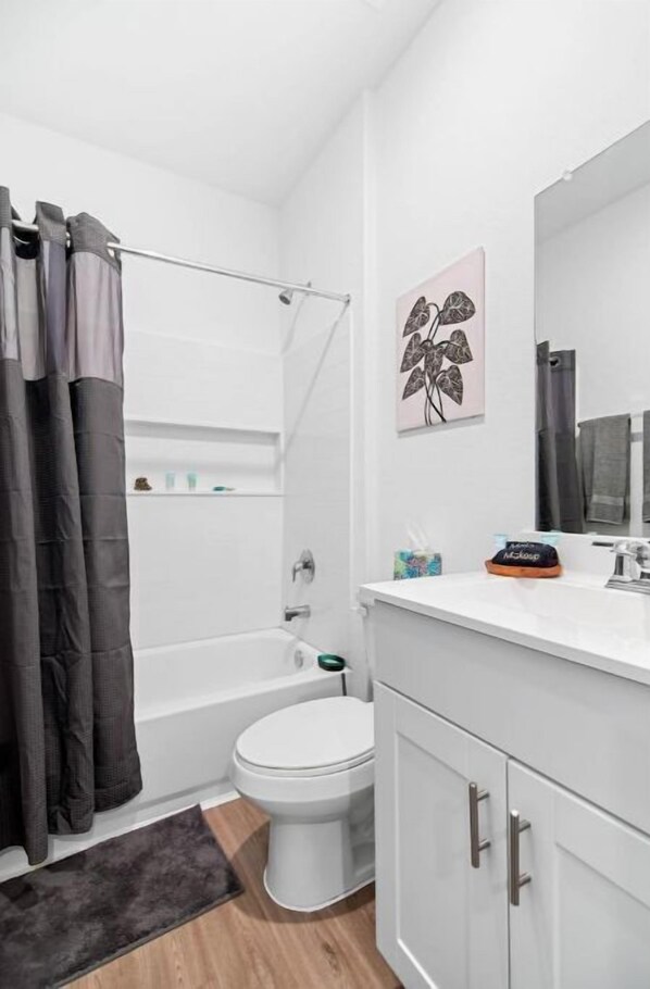 A modern bathroom with a bathtub, toilet, and a vanity with a mirror.