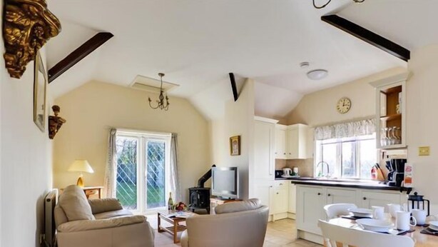 A cozy cottage interior with a living area, a dining table, and a kitchen. - Frome Lodge House (Dorchester)