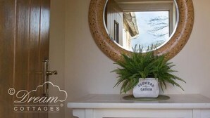A round mirror with a speckled frame, a potted fern, and a door. - Frome Lodge House (Dorchester)