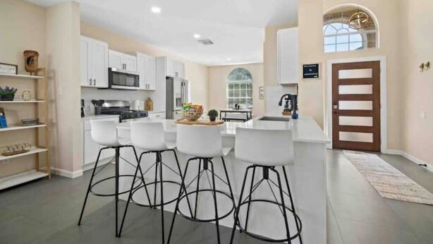 A modern kitchen with white cabinets, a central island, and bar stools.