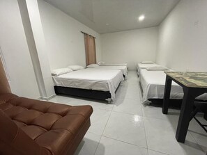 A room with three beds, a brown sofa, and a small table. - MH ROOMS (Cartagena)