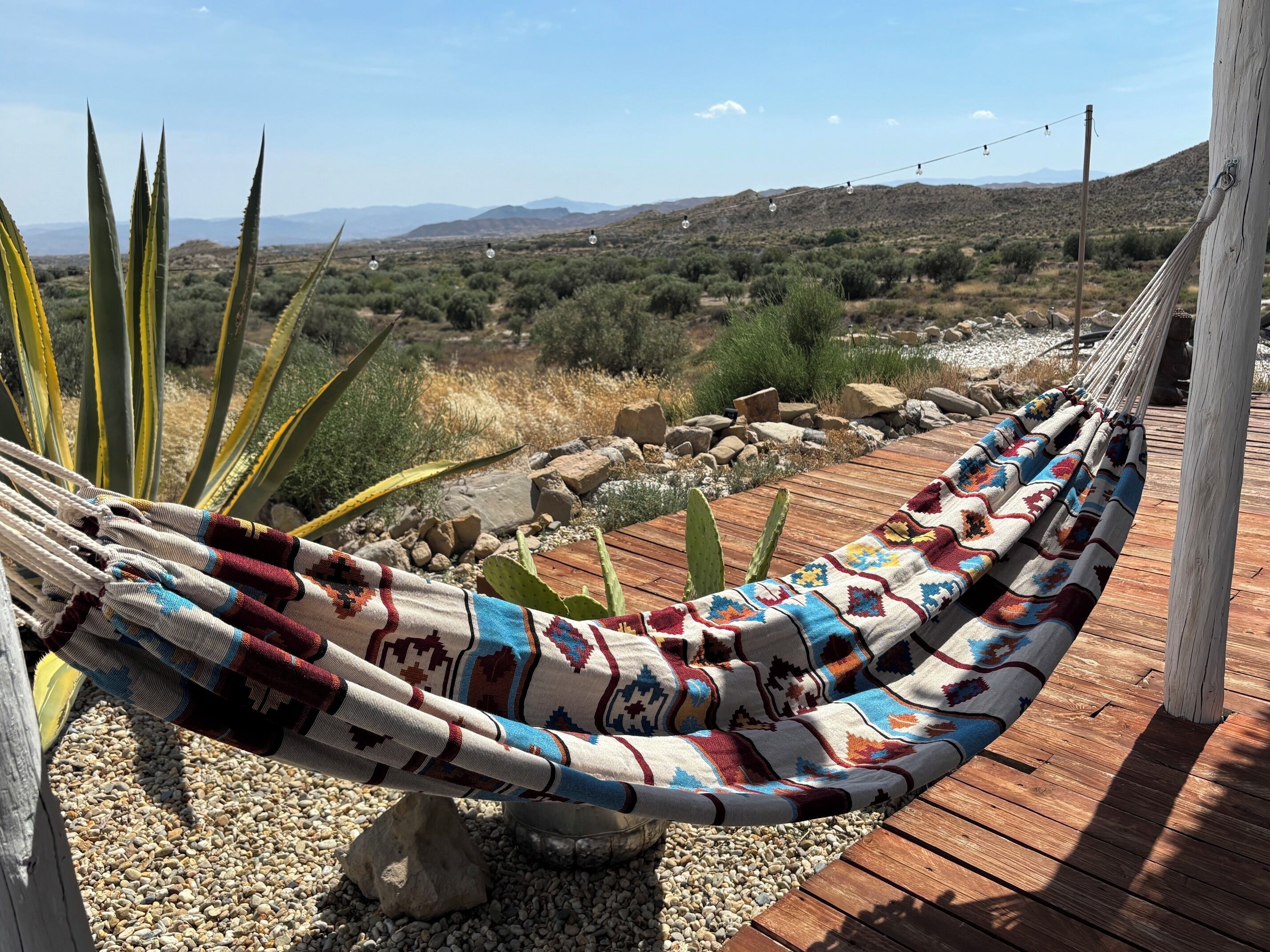 Una hamaca en una terraza de madera con vistas a un paisaje desértico.