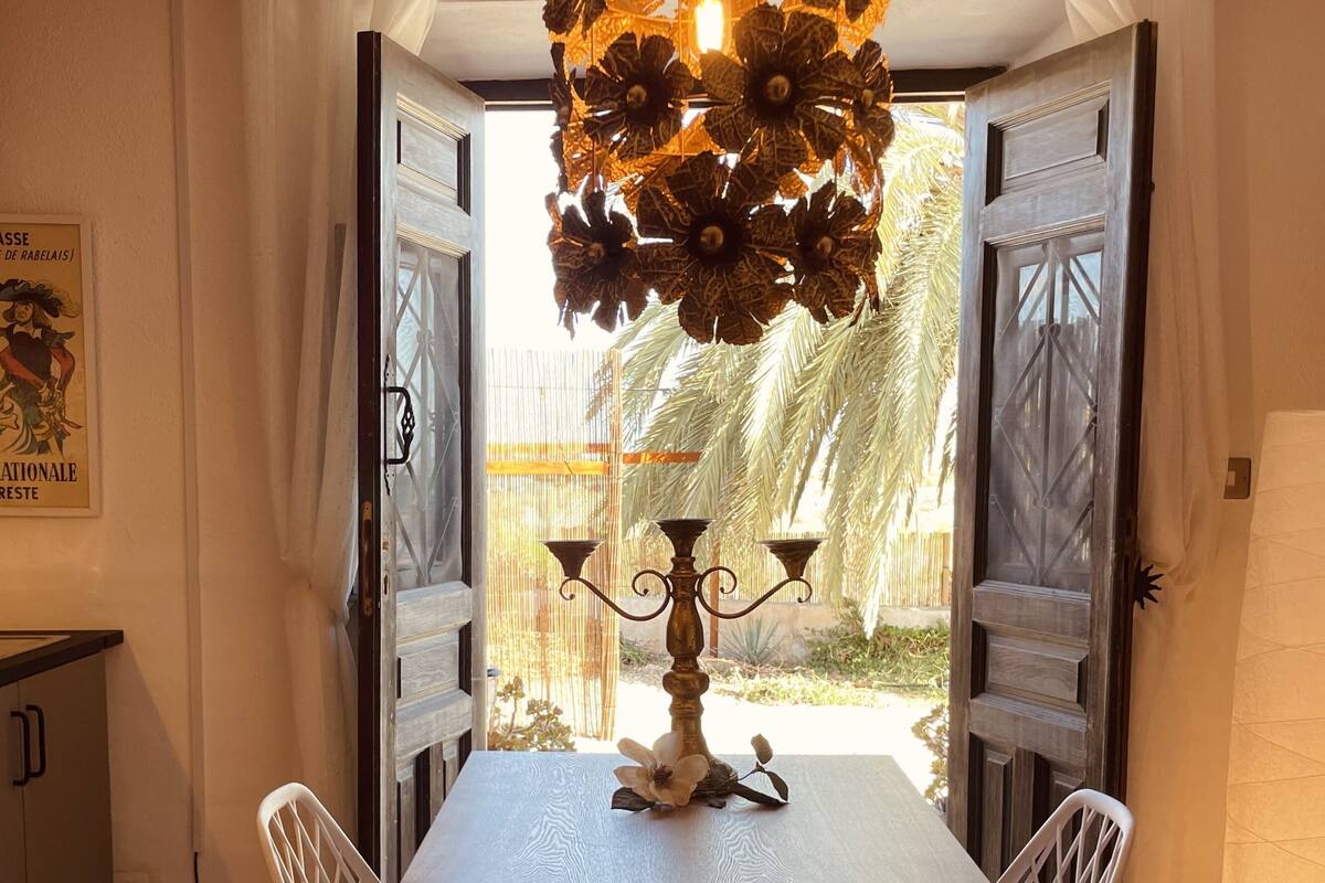 A dining area with a table set for two, a candelabra centerpiece, and a view of a garden with palm trees.