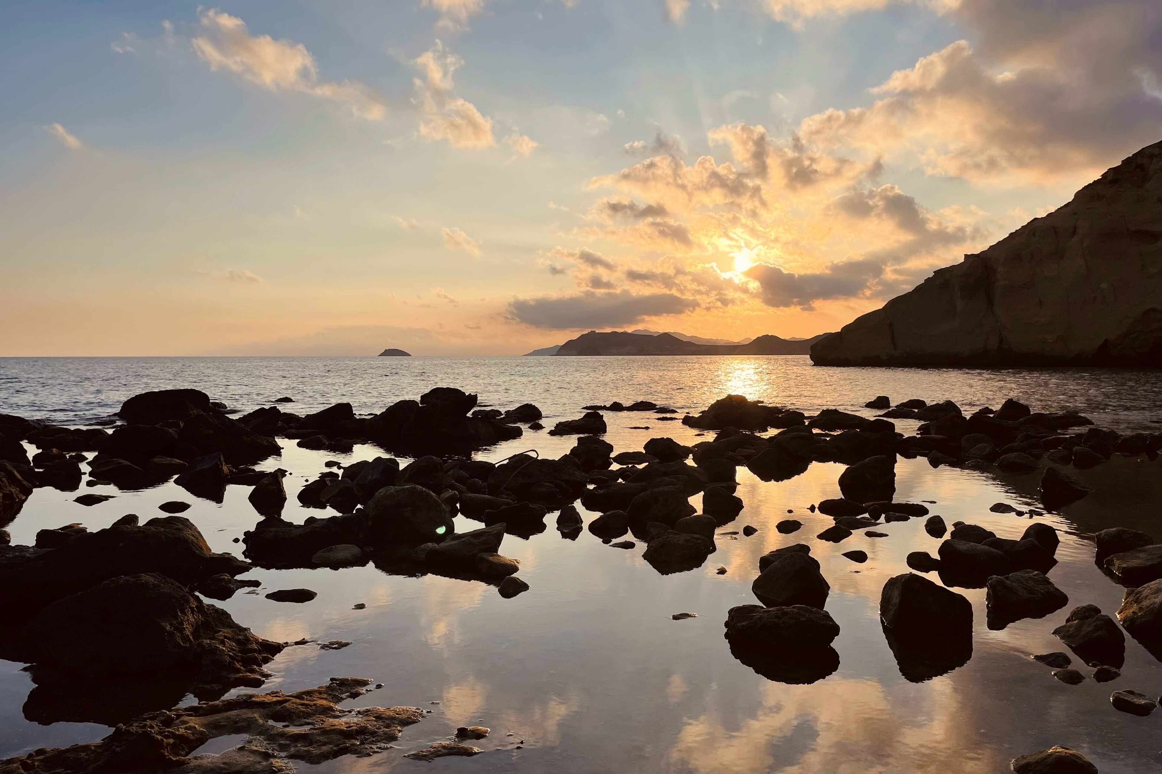 Una costa rocosa con agua tranquila que refleja el cielo.