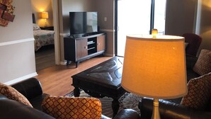 A living room with a sofa, a coffee table, a TV on a cabinet, and a lamp.