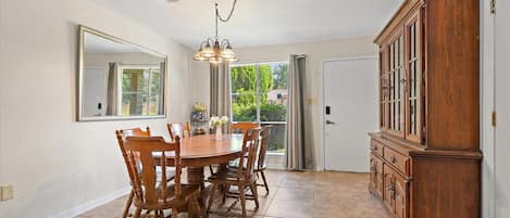 A dining room with a wooden table and chairs, a chandelier, and a large wooden cabinet.