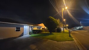 Eine ruhige Wohnstraße bei Nacht mit Häusern, einem gepflegten Rasen und Straßenlaternen.