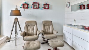 A room with two beige leather chairs, a floor lamp, and a white cabinet with a mirror.