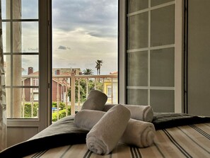 Ein Zimmer mit einem großen Fenster, einem Bett mit gestreifter Kopfteil und zwei zusammengerollten Handtüchern auf dem Bett.