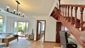 Un vaste espace de vie comprenant un escalier en bois, un canapé, une table basse et un bureau avec une chaise.