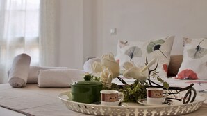 Un plateau de petit-déjeuner soigneusement préparé, avec une théière, des tasses et des fleurs décoratives, posé sur un lit agrémenté d’oreillers ornés de motifs d’oiseaux.