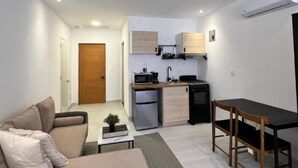 Un espacio habitable pequeño con kitchenette, comedor y sofá.