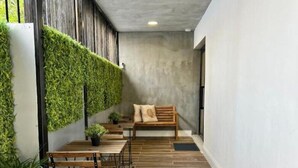 Un couloir doté d’un plancher en bois, d’un banc et d’un mur recouvert de plantes vertes.