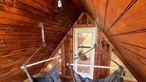 Un intérieur en bois agrémenté de deux hamacs suspendus.