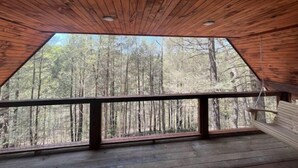 Une cabane en bois dotée d’une grande fenêtre donnant sur une forêt.