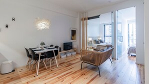 Un soggiorno moderno con zona pranzo, televisione e poltrona in vimini.