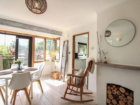 A dining area with a table, chairs, a lamp, and a view of the outdoors.. West Island