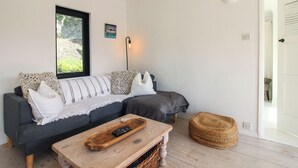 Un salon chaleureux avec un canapé, une table basse en bois et un pouf en fibres tressées.