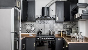 Cocina moderna con armarios negros, un refrigerador de acero inoxidable, una estufa a gas y un salpicadero decorado.