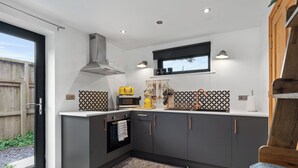 Una cocina moderna con armarios grises, un horno negro y un hervidor amarillo.