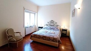 A bedroom with a bed, a chair, a window, and a radiator. - In the greenery of Rome, near Trastevere and the Vatican (Roma)