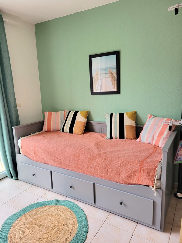 A bedroom with a bed, pillows, a framed picture, and a floor mat.
