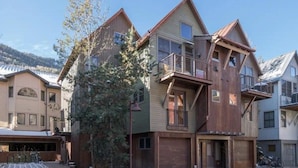 A multi-story residential building with a garage, a balcony, and a tree in front. - OwlMeadows16 3 Bedroom/3 Bath Condo (Telluride)