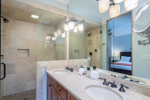 Une salle de bain moderne avec deux lavabos, un grand miroir et un espace douche.