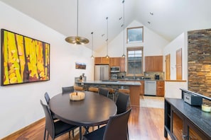 Une cuisine moderne dotée d’un îlot central, de meubles en bois et de luminaires suspendus.