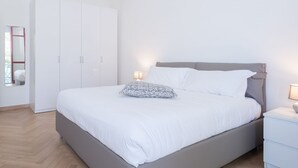 A bedroom with a bed, bedside tables, a wardrobe, and a mirror. - Appartamento Volta 4 (Cernobbio)