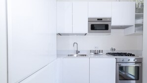 A modern kitchen with white cabinets, a stainless steel oven, a microwave, and a gas stove. - Appartamento Volta 4 (Cernobbio)