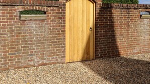 A wooden door with a brick archway, set in a brick wall with small windows. - Orchard Retreat (Tonbridge)