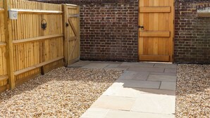 A wooden gate, a brick wall, and a stone pathway leading to a wooden door. - Orchard Retreat (Tonbridge)