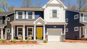 A two-story house with a front porch, a yellow door, and a garage.
