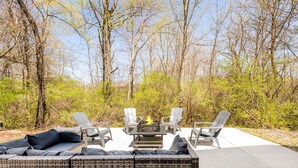 An outdoor seating area with a fire pit, wicker furniture, and white chairs.