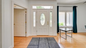 Een nette, goed verlichte ingang met een witte deur, een glazen deur met decoratieve details, en een tafel met metalen frame.