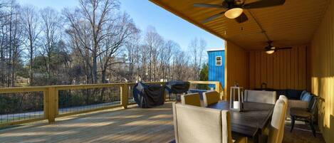 A covered outdoor deck with a dining table, chairs, and a blue structure.
