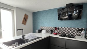A modern kitchen with a black and white backsplash, a built-in stove, and a large window providing natural light. - Gîte à Saulxures sur Moselotte à 1 min du lac (Saulxures-sur-Moselotte)