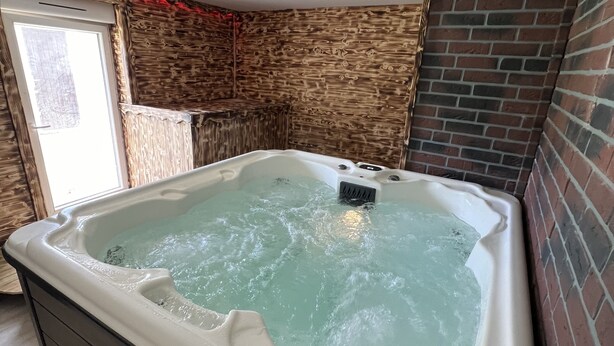 A hot tub in a room with brick walls and a wooden floor. - Gîte à Saulxures sur Moselotte à 1 min du lac (Saulxures-sur-Moselotte)
