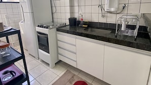 A modern kitchen with white cabinets, a microwave, a coffee machine, and a gas stove. - Ametista 2 (Maceió)