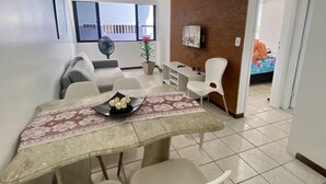 A dining area with a table set for four, a fan, and a TV mounted on the wall. - Ametista 2 (Maceió)