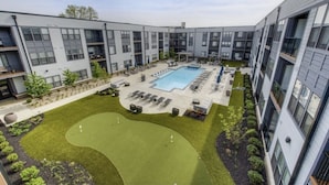 A modern apartment complex with a swimming pool, outdoor seating, and a well-maintained lawn. - *LUXURIOUS 1BED/1BATH - KING BED* -POOL (Fishers)