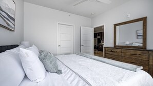 A bedroom with a bed, a dresser, a mirror, and a ceiling fan. - *LUXURIOUS 1BED/1BATH - KING BED* -POOL (Fishers)