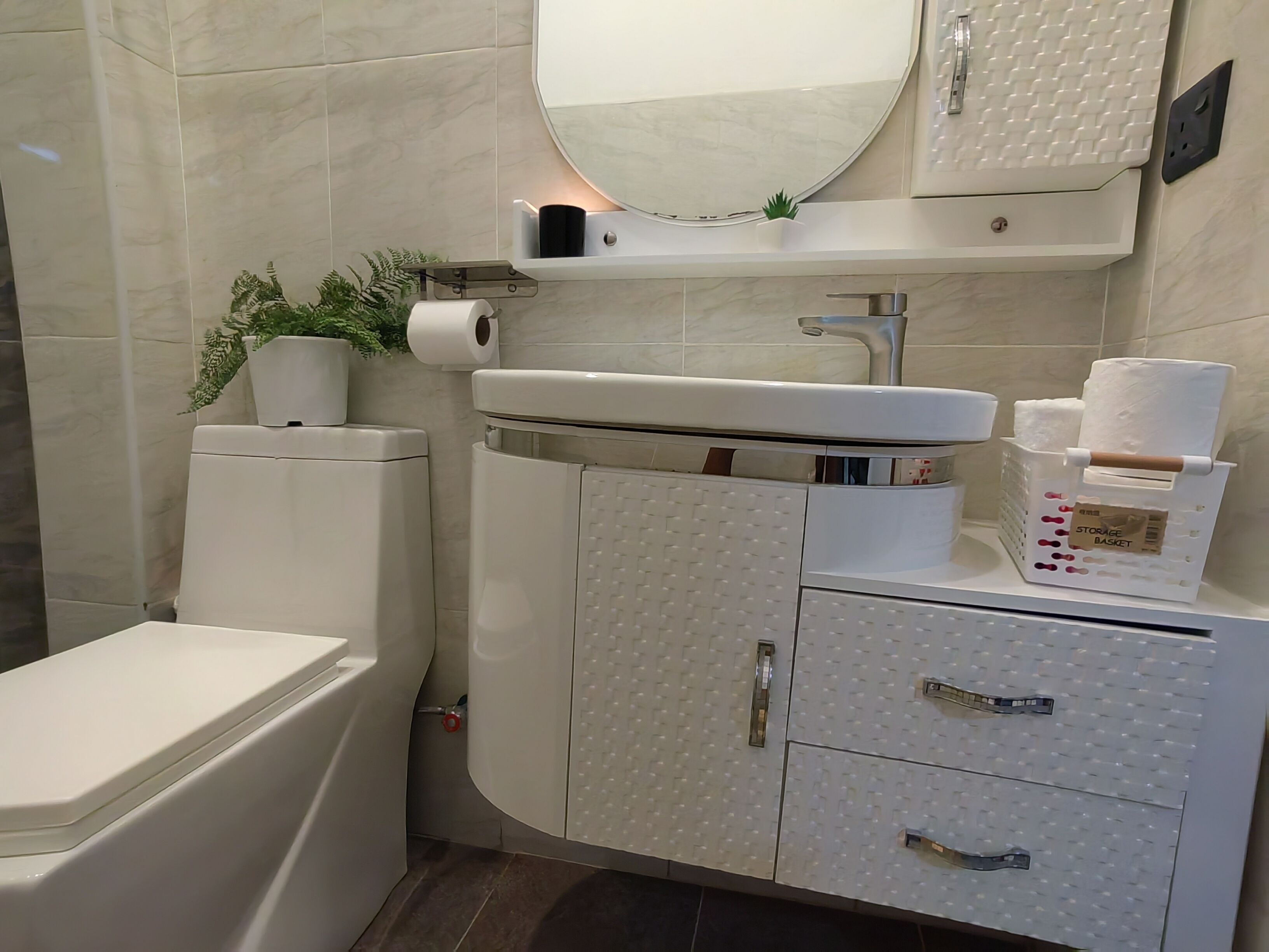 Un baño moderno con inodoro, lavamanos y mueble de almacenamiento.