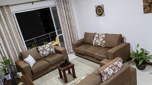 A living room with two sofas, a coffee table, and a TV on a stand. - Breezeskyline with greenery view (Kiambu)