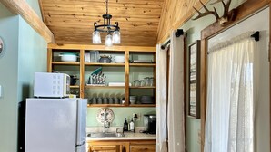 Uma cozinha compacta com armários de madeira, uma geladeira branca e uma lixeira preta.