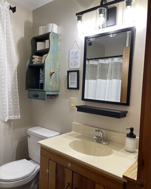 A bathroom with a toilet, sink, and a towel rack with towels. - Wilderness Retreat (Cadiz)