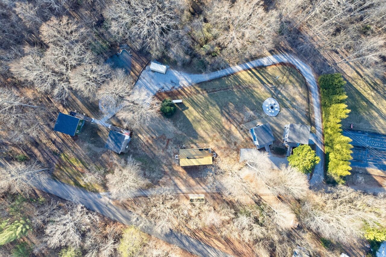 An aerial view of a property with a fenced yard, a small building, and a circular structure.